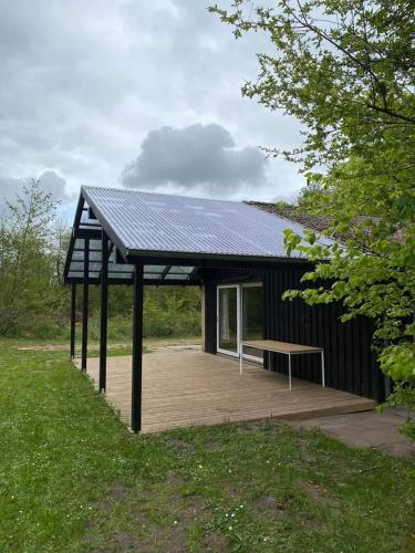 a black building with a bench on a wooden deck at Rosenby Hytten in Dronninglund