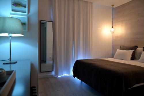 a bedroom with a bed and a mirror and a lamp at Hotel Mar Bravo in Nazaré