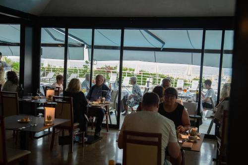 a group of people sitting at tables in a restaurant at Hotel Bristol in Lido di Jesolo