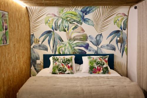 une chambre avec un lit avec un papier peint tropical dans l'établissement Mas des muses, à LʼIsle-sur-la-Sorgue
