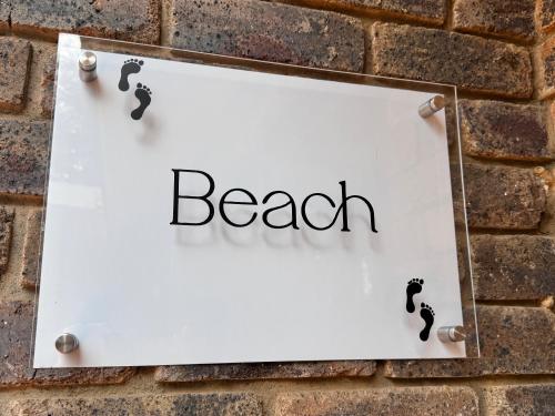 a sign with the word beach on a brick wall at Footprints Self Catering Indoor Heated Pool and Fireplaces in Lanseria