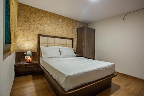 a bedroom with a bed and a night stand with a lamp at Vistavia Villa by StayAtlas in Panchgani