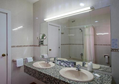 Un baño con dos lavabos y un espejo grande. en Cuatro Naciones, en Barcelona
