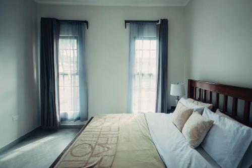 ein Schlafzimmer mit einem großen Bett mit zwei Fenstern in der Unterkunft Garden Villa by Wedelia Homes in Tengeru