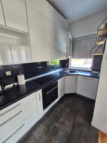 Una cocina con gabinetes blancos y encimeras negras. en Apartman Dvojka Banjaluka, en Banja Luka