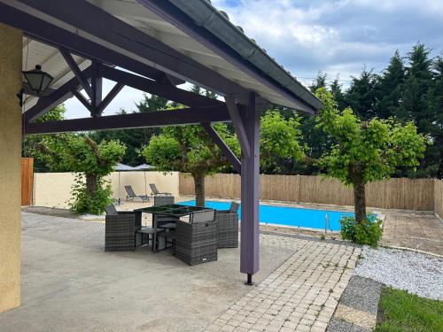 - un pavillon avec une table et des chaises à côté de la piscine dans l'établissement La Maison des Pins - climatisée avec piscine, à Casteljaloux