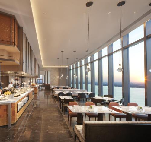 a restaurant with tables and chairs and large windows at Hyatt Regency Changshu Kuncheng Lake in Changshu