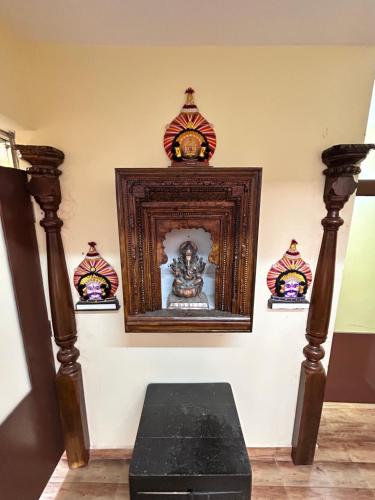 a room with a clock on a wall with a shrine at Shubham Suites & Party Hall in Hubli