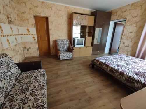 a living room with a bed and a chair at Гостевой домик in Chornomorsk