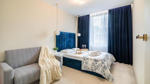 een slaapkamer met een bank, een bed en een tafel bij CONTINENTAL Apartamenty Piamola in Krynica Morska