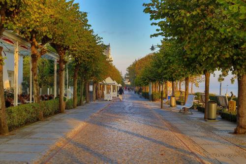a street with trees and a person walking down the street at Ferienwohnung 3 Villa Eden mit Strandkorb in Binz