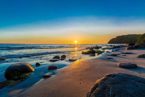 a sunset on a beach with rocks and the ocean at Ferienwohnung 4 Villa Eden in Binz