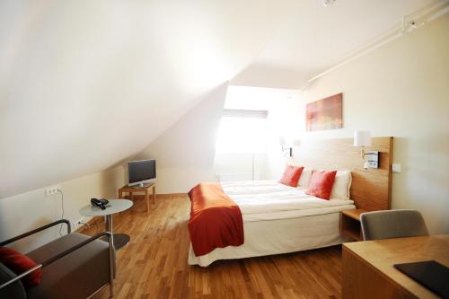 Schlafzimmer mit einem Bett, einem Schreibtisch und einem TV in der Unterkunft City Living Schøller Hotel in Trondheim