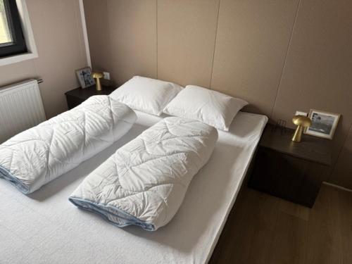two beds with white sheets and pillows in a bedroom at Nieuw in 2025! Modern vakantiehuis aan de Waddenzee in Westerland