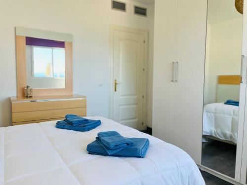 two blue towels sitting on top of a white bed at Apartamento Romanilla Roquetas in Roquetas de Mar