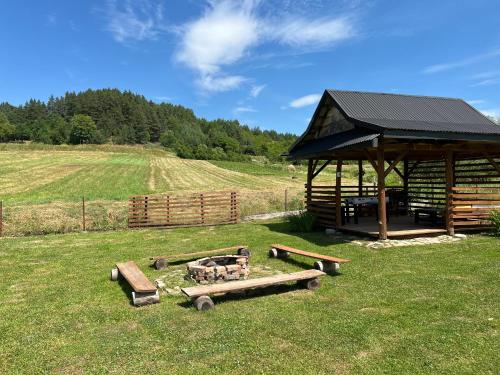 a pavilion in a field with logs in the grass at Domek u Gołąbków Bieszczady in Lesko