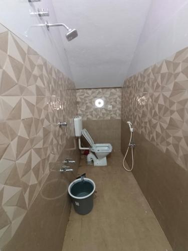 a bathroom with a toilet and a bucket at Christmas Rajan Home Stay in Tirunelveli