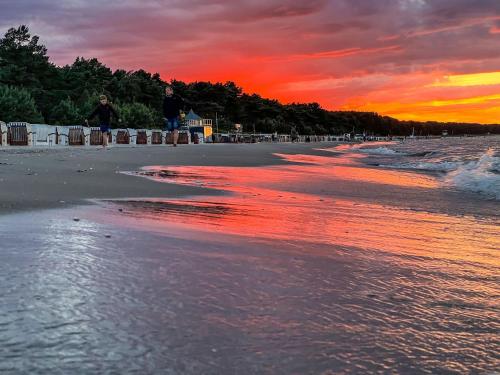 a sunset on the beach with people walking at Villa Strandidyll Apartment 3, Balkon mit Meerblick in Binz