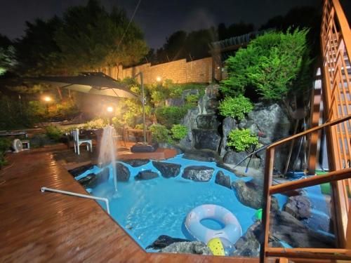 a swimming pool with a waterfall in a backyard at Paju Sabai Pension in Paju