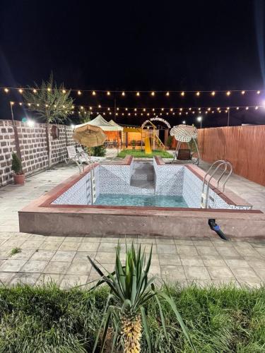 a swimming pool in a backyard at night at Hovakimyans Hotel And Pool Airport in Armavir