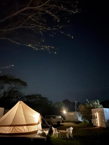 a tent and chairs in a yard at night at ザビーチ in Wada