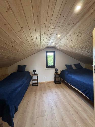 two beds in a room with a wooden ceiling at Domki M&M in Kołczewo