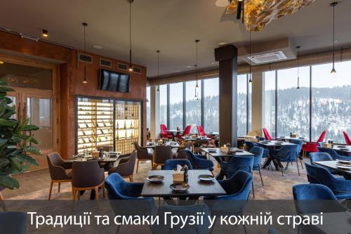 a restaurant with tables and chairs and windows at Fomich Residence in Bukovel