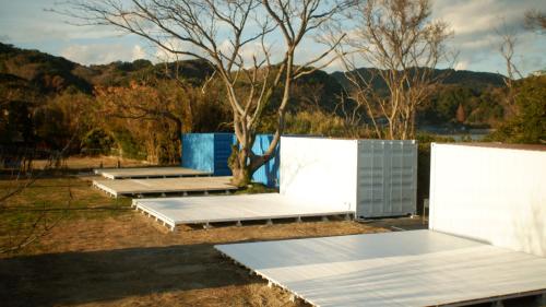 a row of solar panels in a field with a tree at ザビーチ in Wada