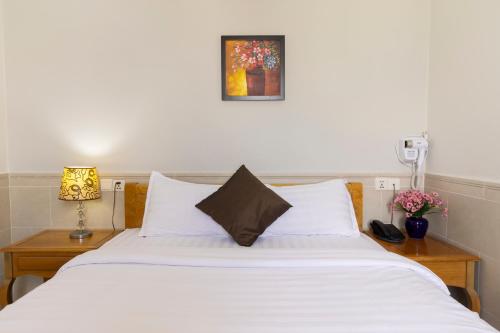 a bedroom with a large white bed with two night stands at California Saigon Hotel in Ho Chi Minh City