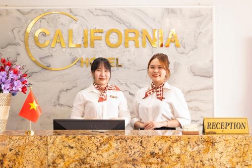 two women standing at a podium with a laptop at California Saigon Hotel in Ho Chi Minh City