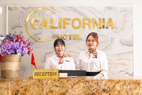 two women standing behind a counter in front of a hotel at California Saigon Hotel in Ho Chi Minh City