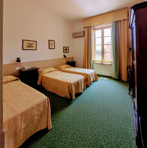 a hotel room with three beds and a window at Hotel Villa Kinzica in Pisa