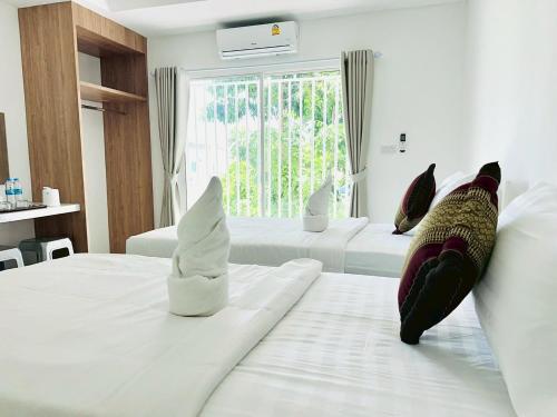 a white bedroom with two beds with pillows on them at Dm สัตหีบ อู่ตะเภา สนามกีฬาราชนาวีสัตหีบ in Sattahip