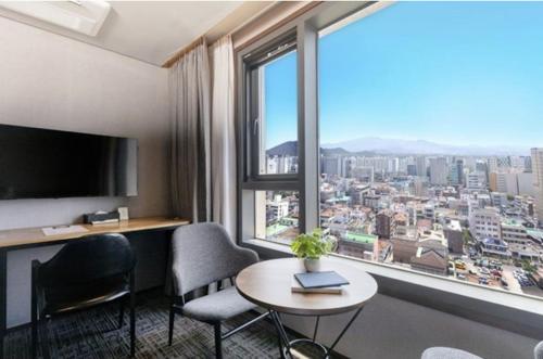a hotel room with a table and chairs and a large window at With Stay Jeju Hotel in Jeju