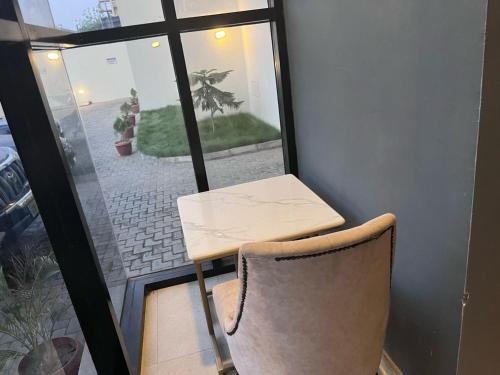 a table and a chair in front of a window at Ridge Apartments in Kano
