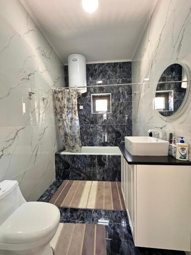 a bathroom with a white toilet and a sink at Ambassador Cottage in Korumdy