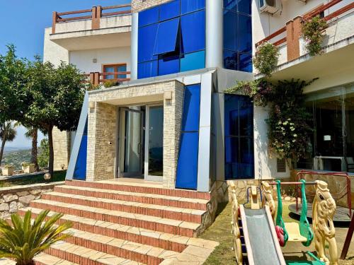 a house with blue walls and stairs in front at Hotel Horizont in Kuçovë