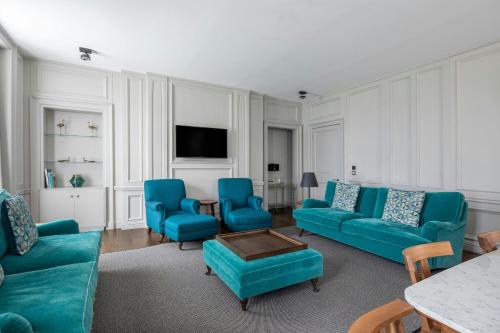 a living room with blue couches and a tv at The Edinburgh Grand, a Luxury Collection Hotel, Edinburgh in Edinburgh