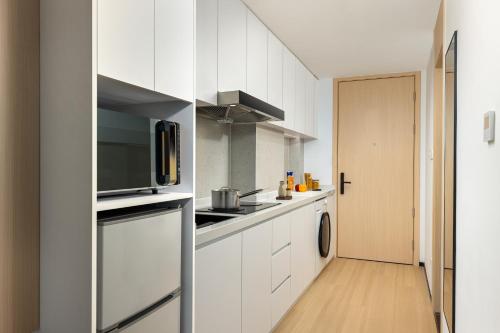 a kitchen with white cabinets and a microwave at Citadines Gongbei Zhuhai in Zhuhai
