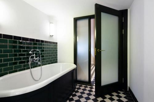 a bath tub in a bathroom with green tile at The Edinburgh Grand, a Luxury Collection Hotel, Edinburgh in Edinburgh