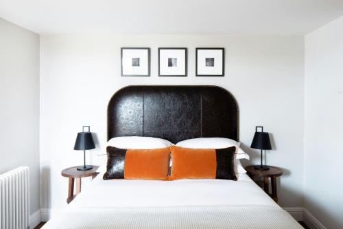 a bedroom with a black headboard and orange pillows on a bed at The Edinburgh Grand, a Luxury Collection Hotel, Edinburgh in Edinburgh