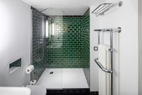 a bathroom with a tub and a green tiled wall at The Edinburgh Grand, a Luxury Collection Hotel, Edinburgh in Edinburgh