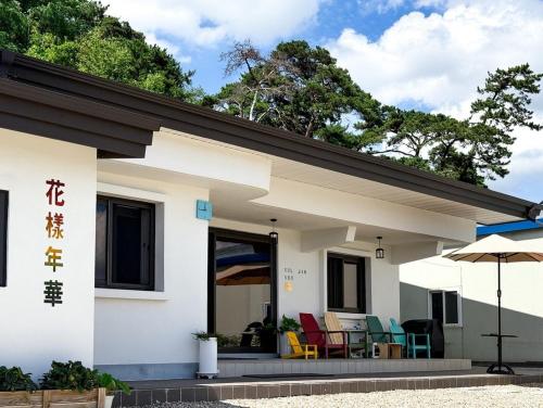 a white house with colorful chairs and an umbrella at Buan Hwayangyeonhwa Pension in Buan