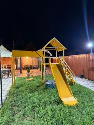 a playground with a slide in the grass at night at Hovakimyans Hotel And Pool Airport in Armavir