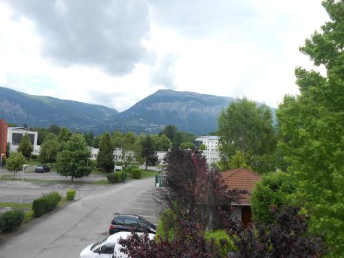 a street with cars parked in a parking lot with mountains at Premiere Classe Grenoble Sud - Gieres Universite in Gières