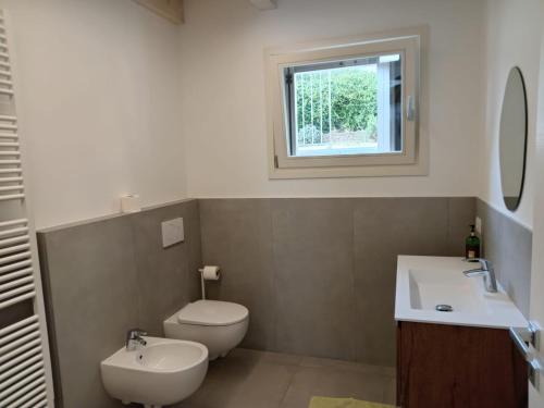 a bathroom with a toilet and a sink and a window at Le Casette CINQUE in Pacengo di Lazise