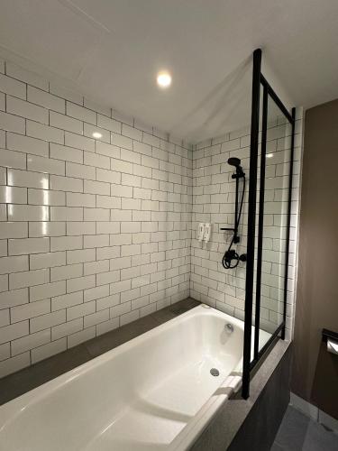 a bath tub in a bathroom with white tiles at Citadines Connect Airport Jakarta in Tangerang