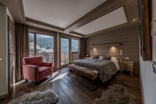 a bedroom with a bed and a chair and windows at 4 Bedrooms Penthouse in Courchevel 1650 in Courchevel