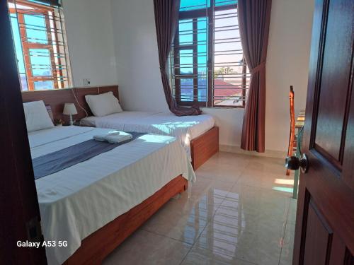 twee bedden in een kamer met twee ramen bij GolDen RiCe in Thái Thụy