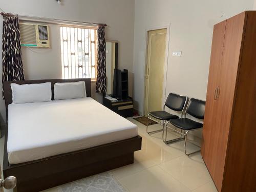 a bedroom with a bed and two chairs in it at Lake Land Guest House in Kolkata